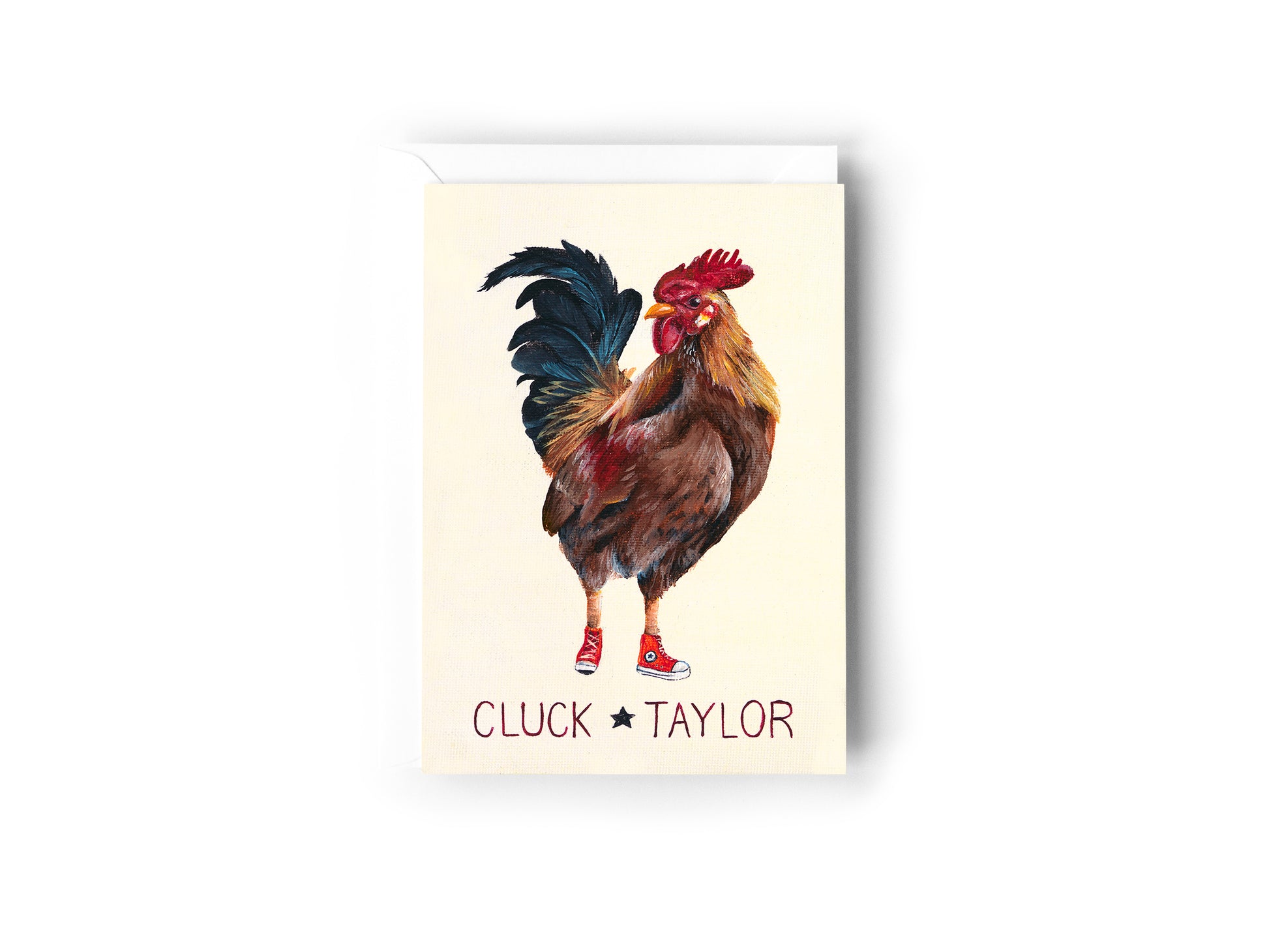 A greeting card design hand painted by Australian Artist Jessica Alpert of a rooster wearing red converse shoes on a cream background. The words 'Cluck Taylor' are written below the rooster. The card has a white envelope behind it and sits on a white background.