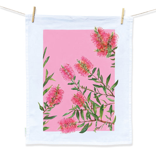 A hot pink floral tea towel featuring pink Australian bottlebrush and green leaves with a thick white border by Australian Artist Jessica Alpert.