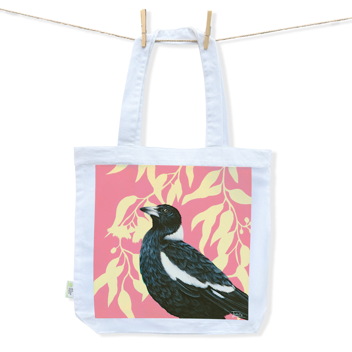 Australian Artist Jessica Alpert designed and hand painted an Australian magpie illustration on a vibrant pink background with yellow silhouette gum leaves and flowers on a white tote bag. 