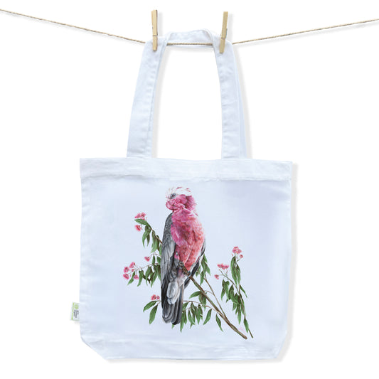 White tote bag featuring a detailed design of a pink Australian Galah perched on a branch of pink flowering gum by Australian Artist Jessica Alpert.